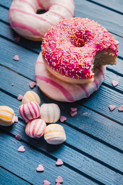 Drei leckere donuts und bunte süßigkeiten | Kostenlose Foto
