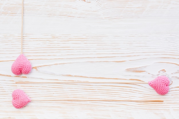 Drei rosa gestrickte herzen auf stöcken auf einem weißen hölzernen hintergrund Premium Fotos