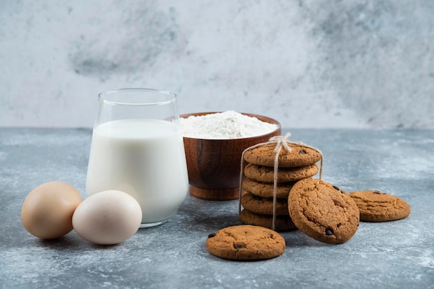 Ein glas heiße milch mit leckeren keksen auf einem grauen