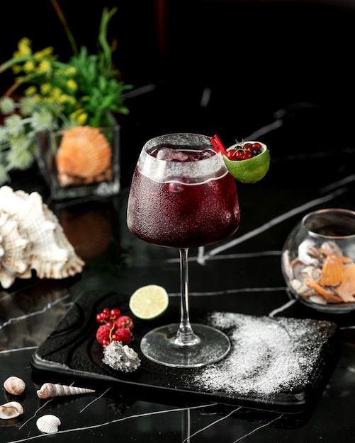 Ein glas roter cocktail, garniert mit limettenschale und