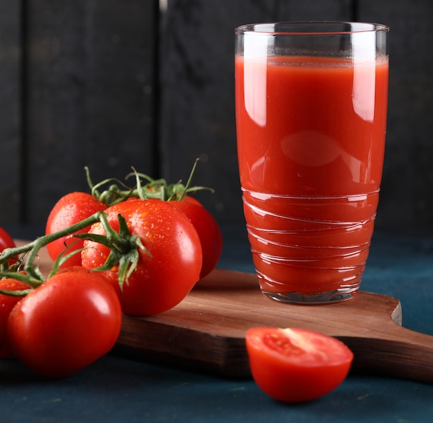 Ein glas tomatensaft, ganze und geschnittene tomaten