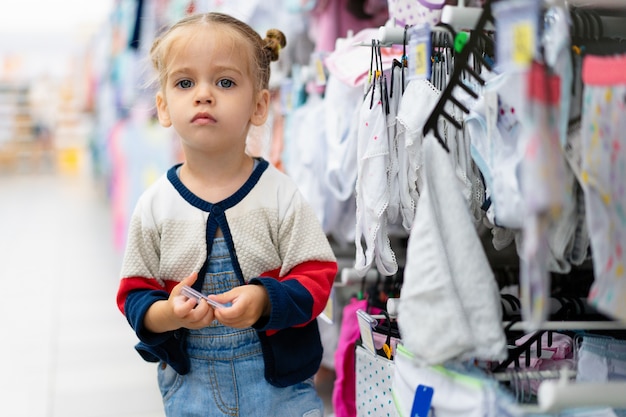 Ein Kleines Kaukasisches Madchen Steht Nahe Einem Schaufenster Mit Kleidung Und Unterwasche In Einem Grossen Speicher Premium Foto