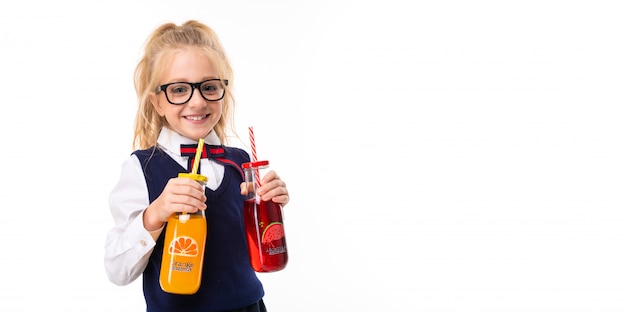 Ein Kleines Madchen Mit Blonden Haaren Die In Einen Pferdeschwanz Gestopft Sind Grossen Blauen Augen Und Einem Niedlichen Gesicht In Quadratischen Schwarzen Glasern Halt Orangen Und Wassermelonensaft In Einer Glasflasche Premium Foto