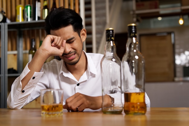 Ein mann, der in der kneipe sitzt, weint wegen seiner traurigkeit und möchte es durch alkoholkonsum vergessen. Premium Fotos
