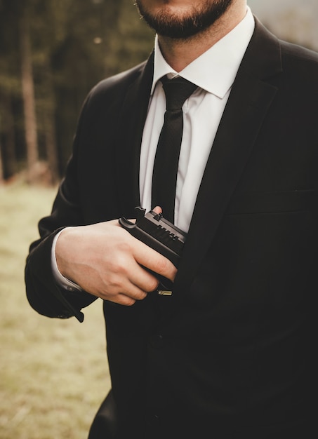 Ein Mann Im Anzug Mit Bart Jacke Und Weissem Hemd Schwarzer Krawatte Und Einer Pistole In Der Hand Auf Der Strasse Premium Foto