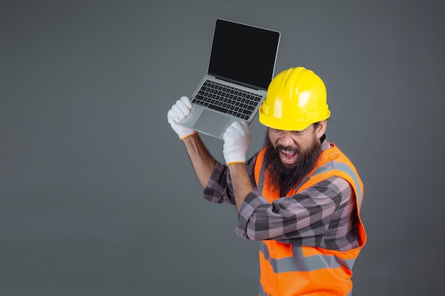 Ein technikmann, der einen gelben sturzhelm hält ein notizbuch auf einem grau trägt. Kostenlose Fotos