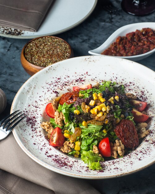 Ein teller mit grünem salat mit salat, tomaten, walnuss, mais und ...