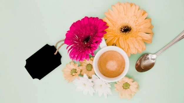 Eine draufsicht der kaffeetasse mit blumendekoration und schwarzem leerem tag auf farbigem hintergrund Kostenlose Fotos
