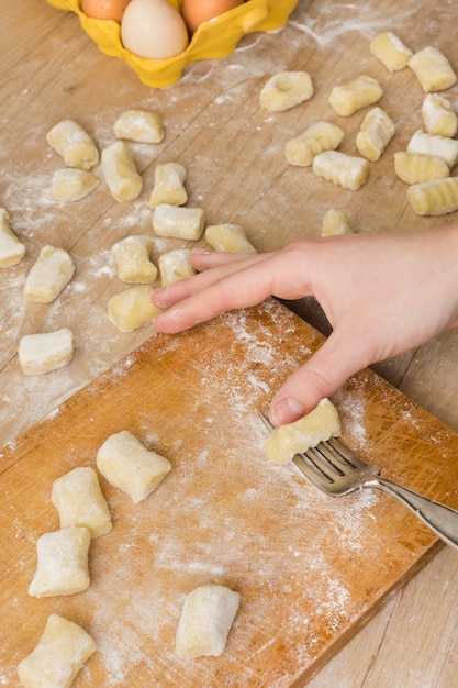 Eine draufsicht einer person, die den teigwaren-gnocchi-teig auf schneidebrett zubereitet Kostenlose Fotos