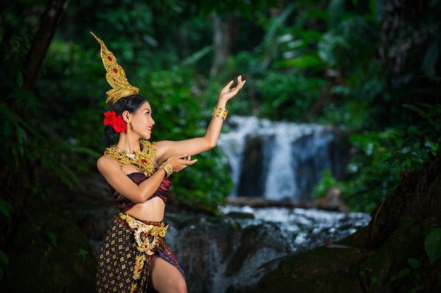 Eine frau kleidete sich mit einem alten thailändischen kleid am wasserfall an. Kostenlose Fotos