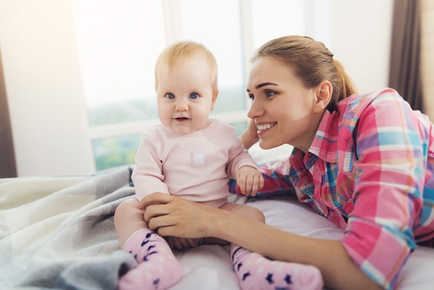 Eine frau liegt neben dem baby auf dem bett. | Premium-Foto