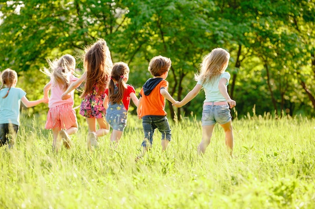 Eine gruppe kinder, die in den park auf einem grünen gozon spielen und laufen. Premium Fotos