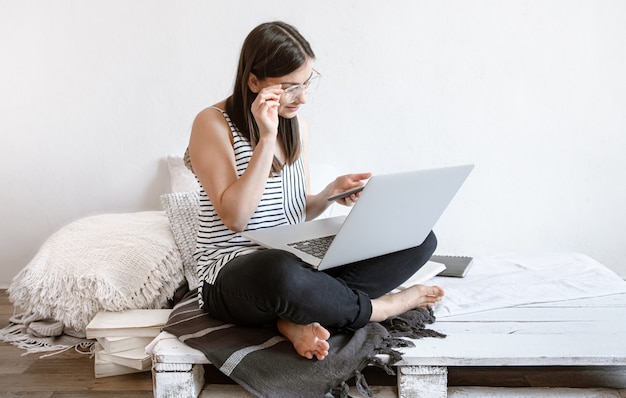 Eine junge frau arbeitet zu hause an einem computer ...