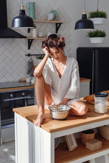 Eine Lustige Frau Mit Locken Im Weissen Bademantel Fuhlt Traurigkeit Und Mudigkeit In Der Kuche Beim Kochen Premium Foto