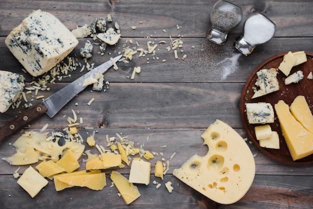 Eine obenliegende ansicht des salz- und pfefferstreuers mit käse auf hölzernem schreibtisch Kostenlose Fotos