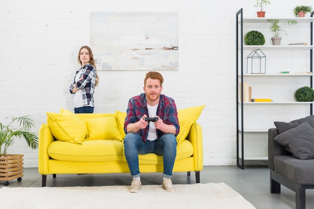 Eine verärgerte junge frau, die hinter dem gelben sofa mit ...