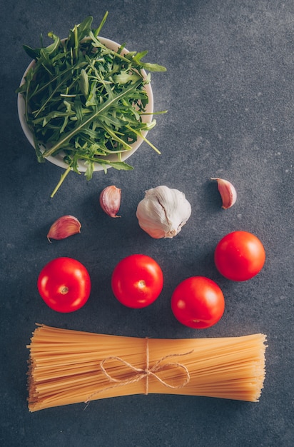 Einige spaghetti-nudeln mit gemüse, tomaten und knoblauch auf grauem ...