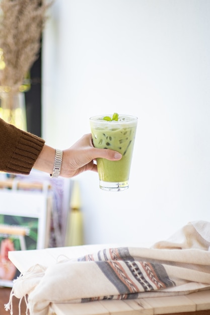 Eisgrüner tee oder matcha latte auf hohen gläsern mit stroh auf weißer hölzerner tabelle und kleidungsdekorationsgegenstand. Premium Fotos