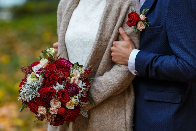 Elegante Braut Im Kleid Mit Spitze Die Brautstrauss Der Blumen In Den Rosa Und Grunen Farben Halt Und Brautigam Im Dunkelblauen Anzug Mit Boutonniere Premium Foto