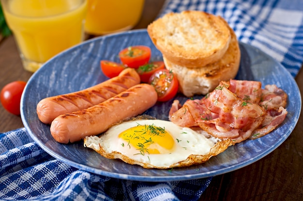 Englisches frühstück - toast, ei, speck und gemüse im rustikalen stil ...