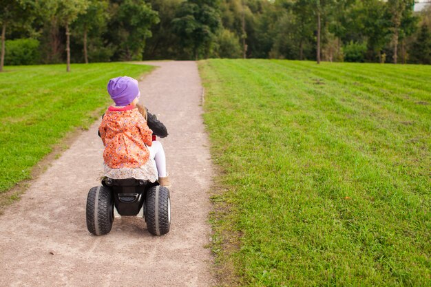 Entzückende kleine süße mädchen fahren draußen ein motorrad Premium Fotos