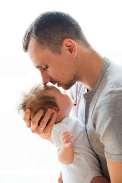 Erwachsener vater, der baby in der stirn küsst Kostenlose Fotos