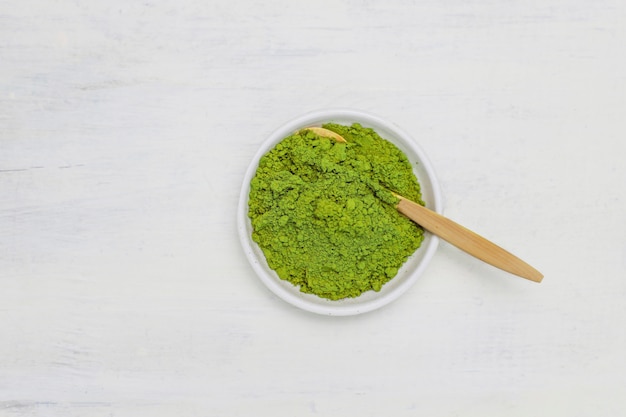 Fassen sie das matcha ab, das vom pulverisierten grünen tee matcha und vom bambuslöffel auf weiß gemacht wird. kopieren Kostenlose Fotos