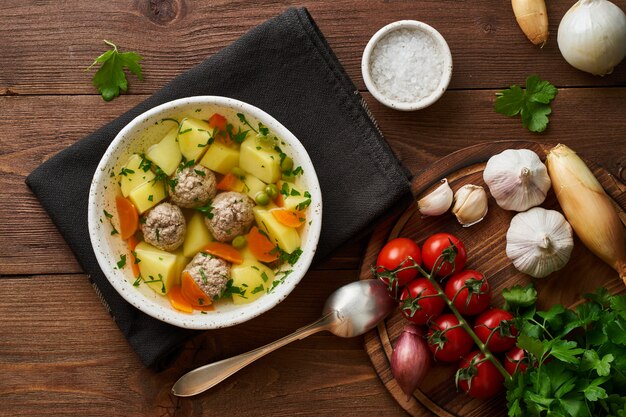 Fleischklöschensuppe in der weißen platte auf alter hölzerner rustikaler brauner tabelle Premium Fotos