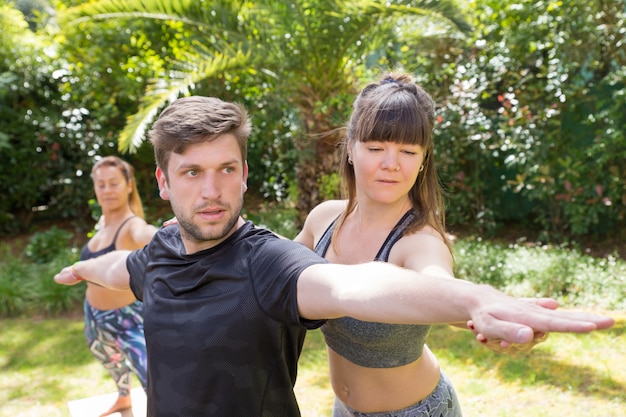 Fokussierter yogalehrer, der newby hilft Kostenlose Fotos