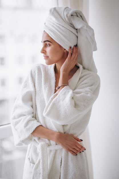 Frau, die am fenster im bademantel steht Kostenlose Foto