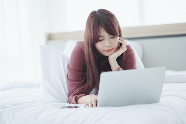 Frau, die an einem laptop arbeitet, der auf dem bett im