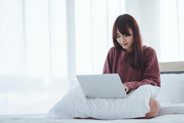 Frau, die an einem laptop arbeitet, der auf dem bett im