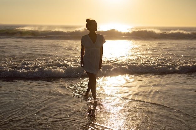 Frau, die auf meer am strand geht Kostenlose Foto