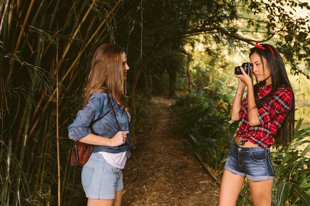 Frau, die die fotografie ihres freunds mit kamera im wald anklickt Kostenlose Fotos