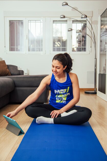 Frau, die yoga zu hause praktiziert und einen onlinekurs