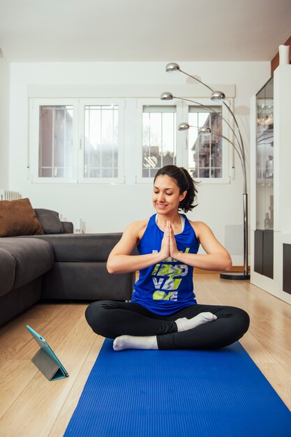 Frau, die yoga zu hause praktiziert und einen onlinekurs