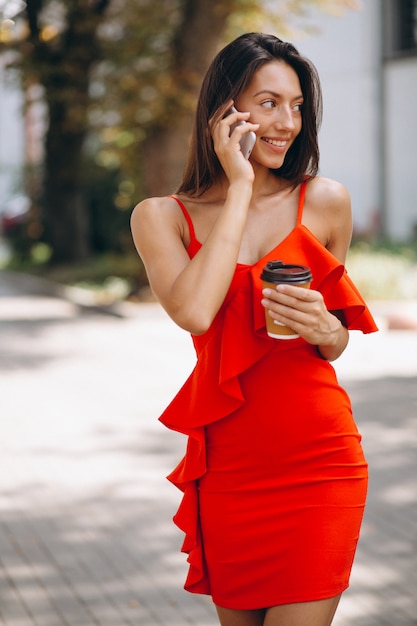  Frau  im roten kleid  unter verwendung des telefons und des 