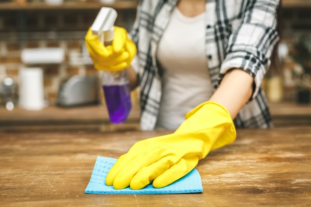 Frau in der küche, die staub mit einem spray und einem