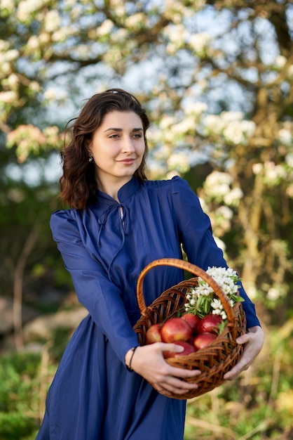 Frau in einem blauen kleid steht in einem blühenden garten