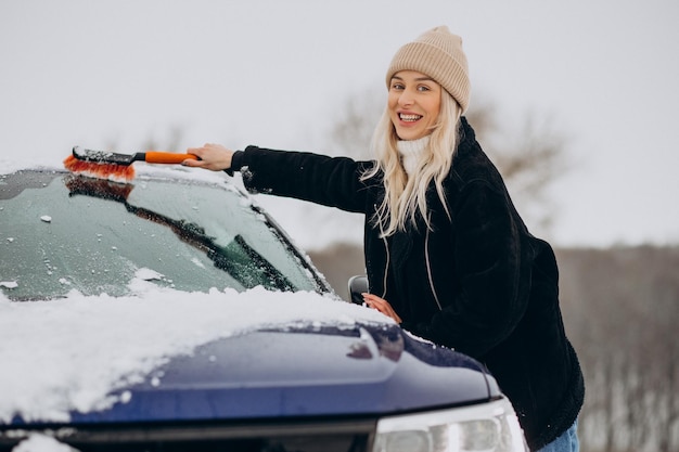 Frau putzt ihr fensterauto vom schnee Kostenlose Foto