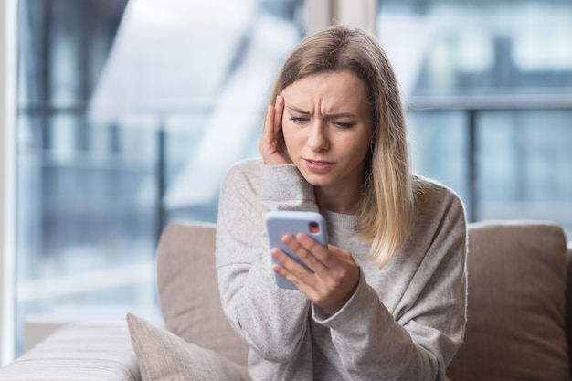 Frau sitzt zu hause auf der couch mit starken