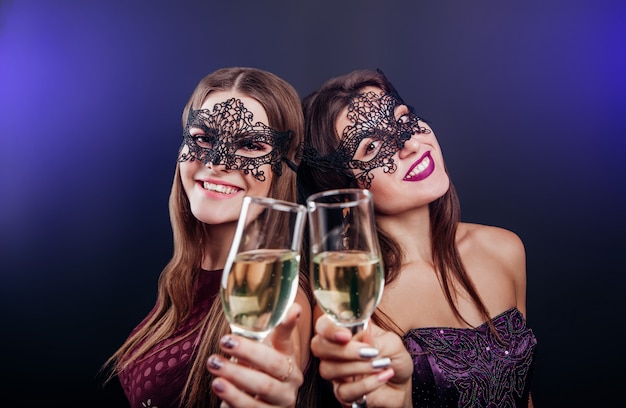 Frauen feiern silvester champagner trinken auf maskerade-party Premium Fotos