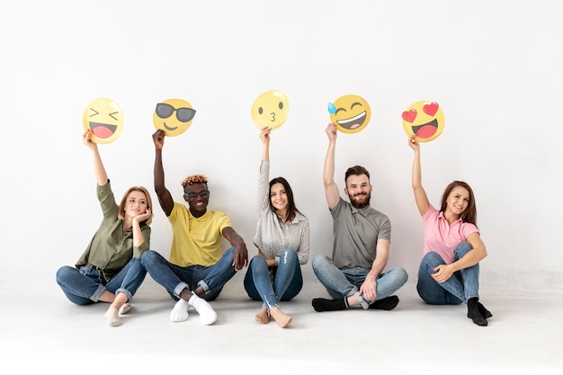 Freunde sitzen auf dem boden und halten emoji | Kostenlose ...