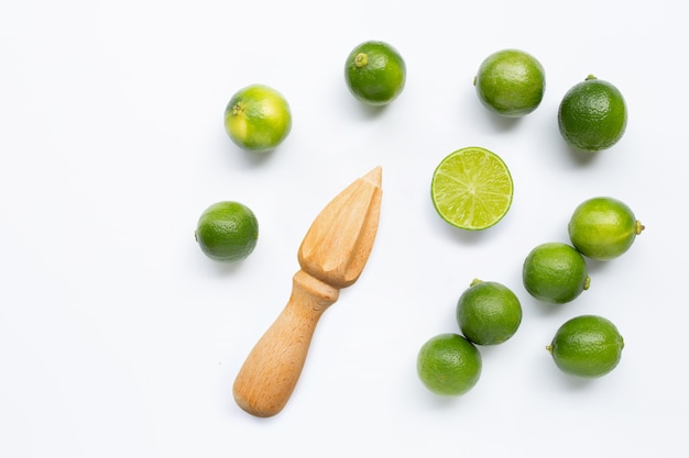 Frische kalke und hölzerner juicer auf weiß. Premium Fotos