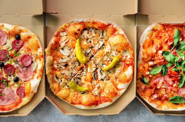 Frische pizza im lieferungskasten auf grauem konkretem hintergrund. draufsicht, raum kopieren Premium Fotos