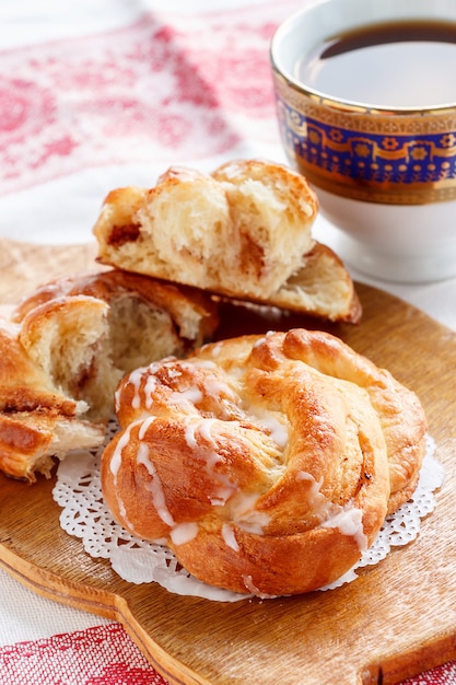 Frisches selbst gemachtes süßes zimtstrudelbrötchen mit glasur und schwarzem kaffee zum frühstück. Premium Fotos