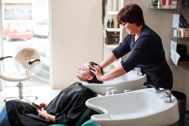 Friseur und frau während der haarwäsche Premium Fotos