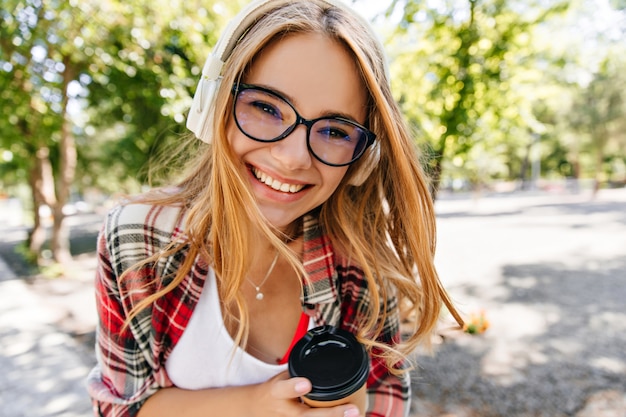 Frohliche Junge Dame In Glasern Die Kaffee Im Park Geniessen Foto Im Freien Des Gluckseligen Kaukasischen Madchens Das Spass Im Freien Hat Und Musik Hort Kostenlose Foto