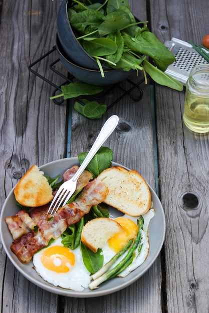 Frühstück auf einem teller rührei mit toastbrot, speck und aromatischen ...