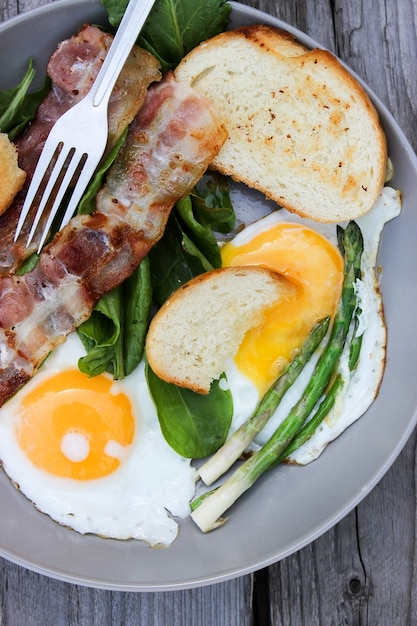 Frühstück auf einem teller rührei mit toastbrot, speck und aromatischen ...